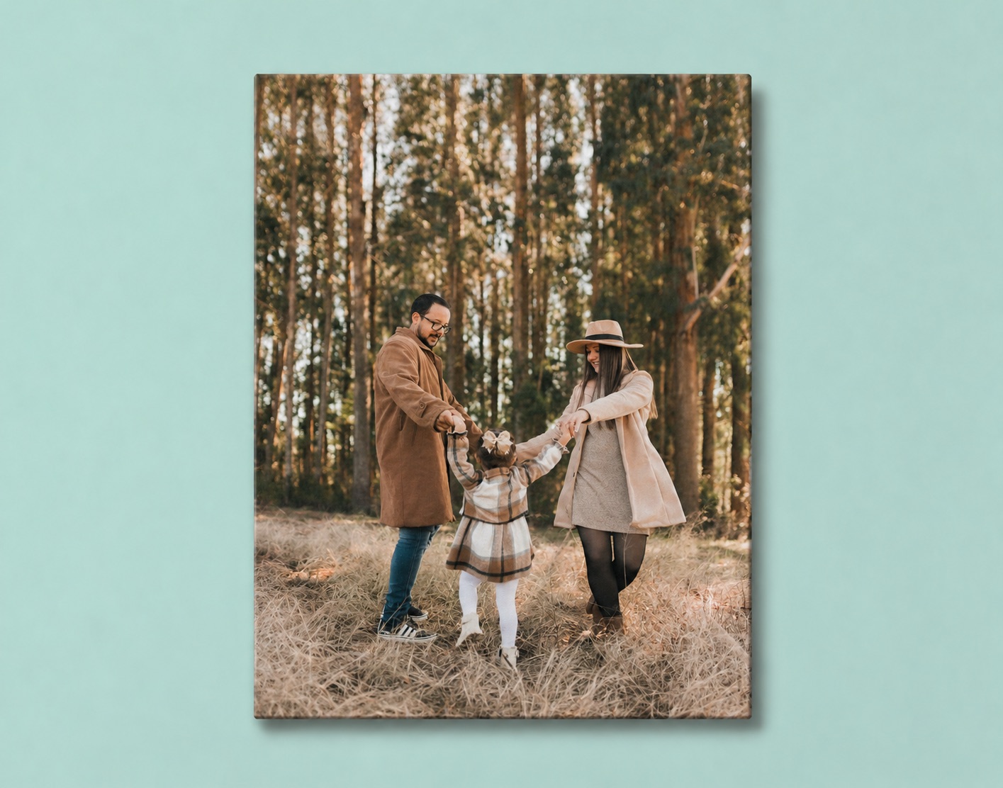 A family canvas print of parents swinging their little girl between them in a pine forest