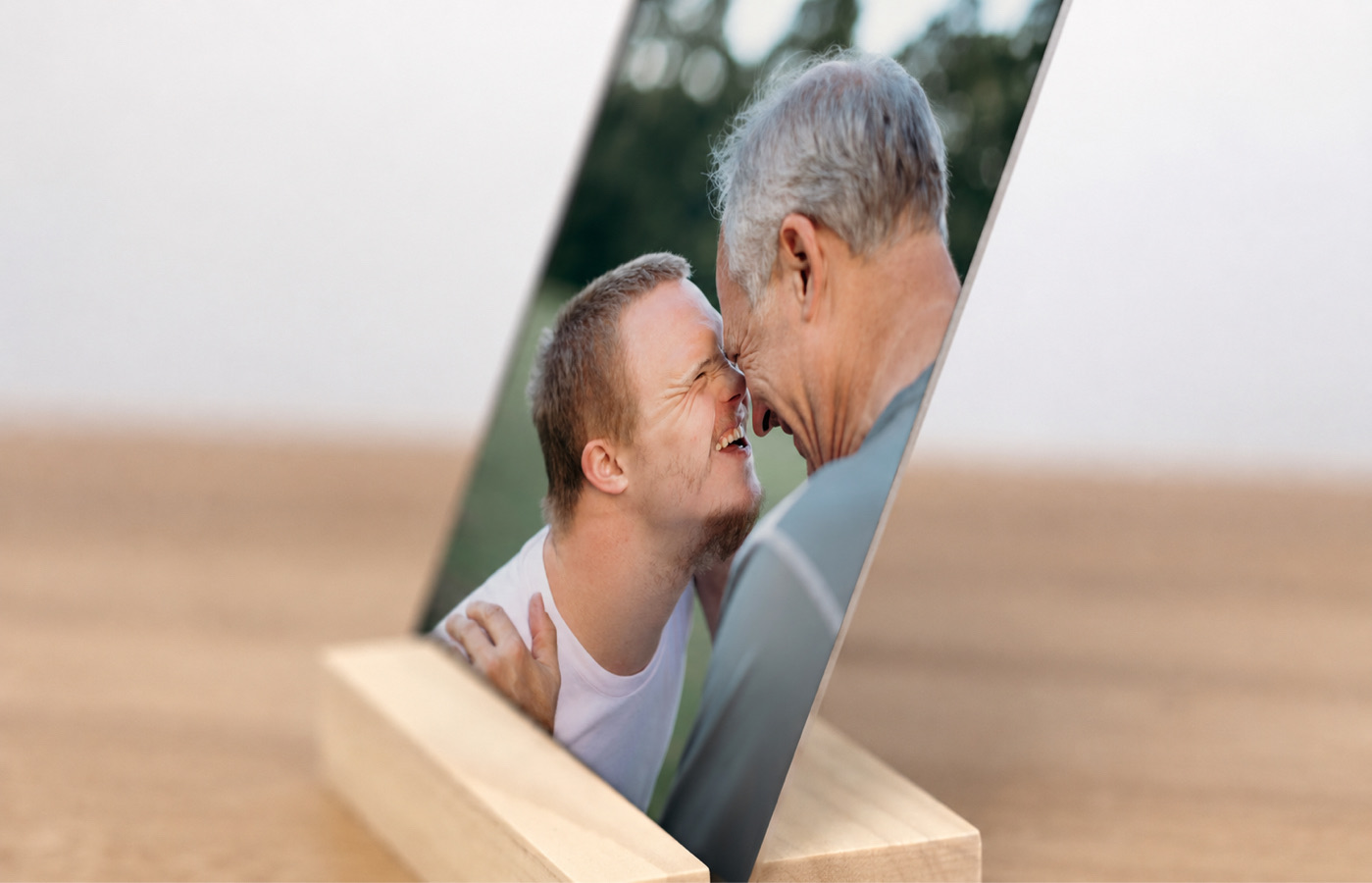 Side view of a family desk print of a father and son touching foreheads, resting in its solid wood stand