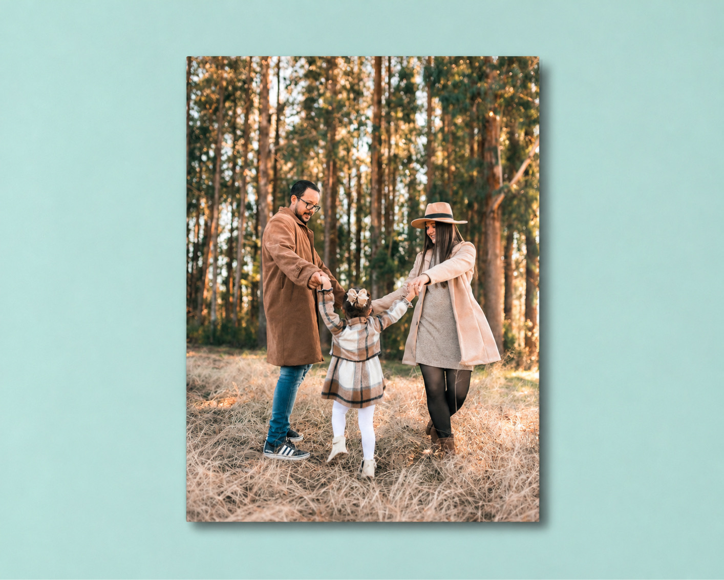 A family metal print of parents swinging their little girl between them in a pine forest