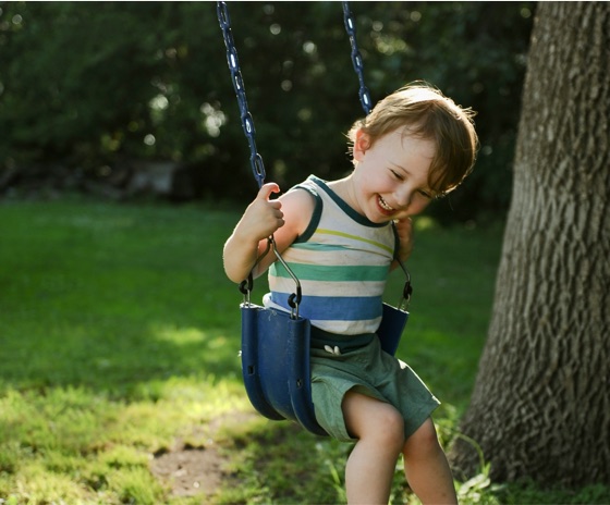 A metal print of a smiling toddler on a backyard swing