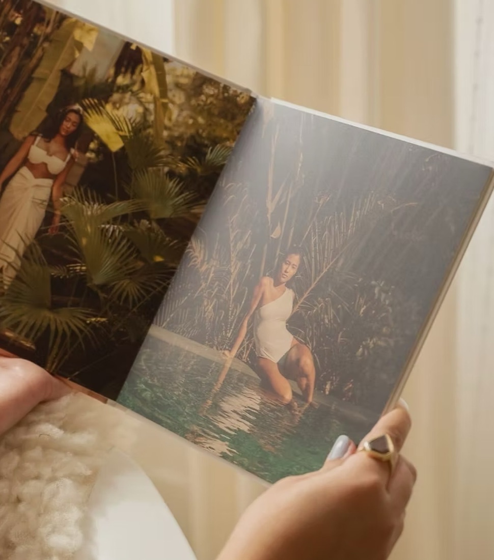 Hands holding open a layflat photo book, its photos running flat across both pages