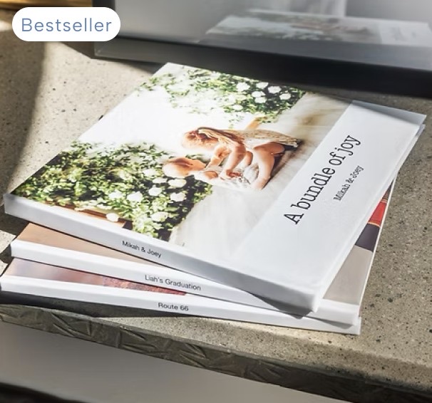 A stack of hardcover photo books in the sun, the top one titled A bundle of joy, with a Bestseller tag