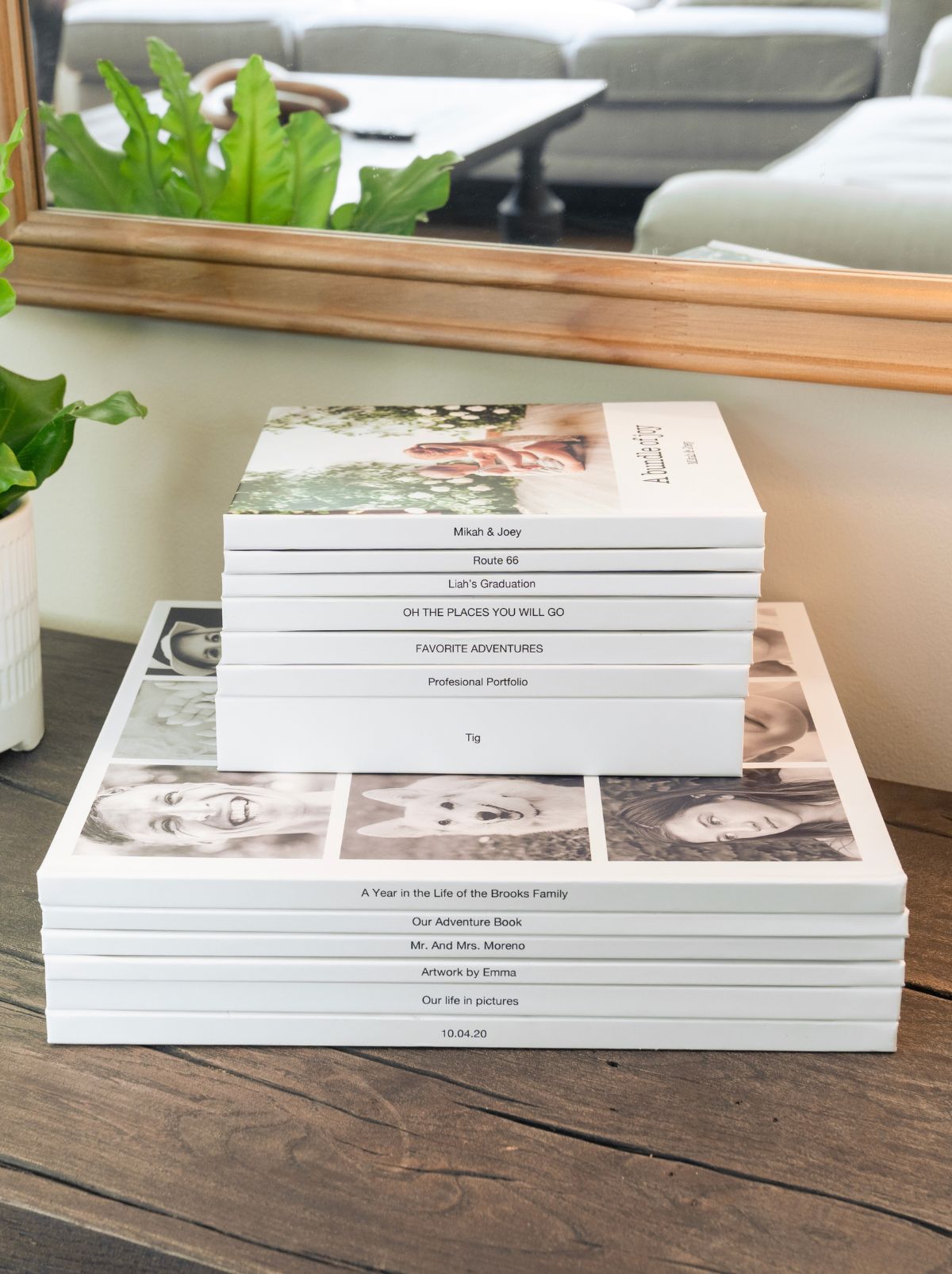 A stack of hardcover photo books on a wooden table, each spine printed with its own title