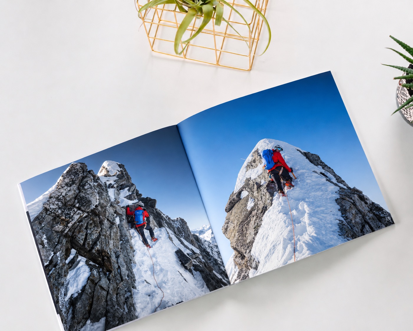 A travel photo book open to two photos of a climber on a snowy mountain ridge
