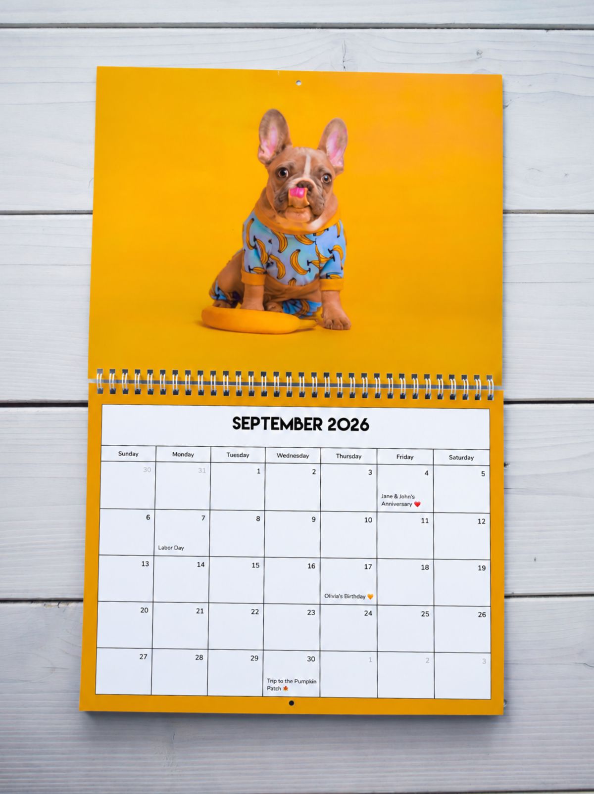 A wall calendar open to September 2026, with a French bulldog in banana pajamas above the month grid